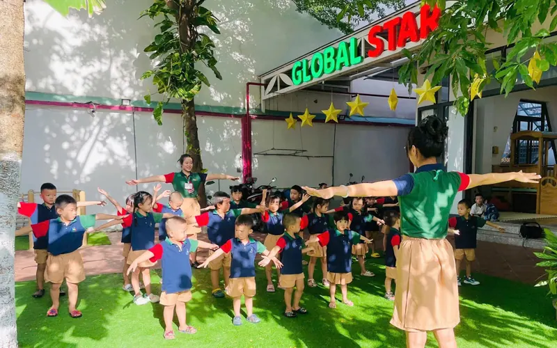 Cả lớp mầm non tập thể dục trên sân cỏ dưới biển Global Star